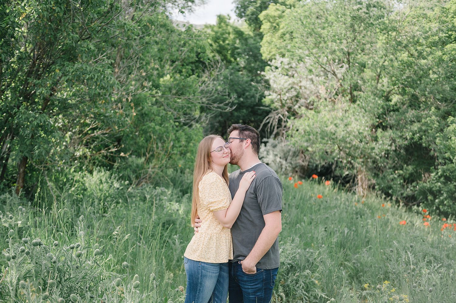 Couple sharing an intimate moment outdoors in a lush green summer setting.