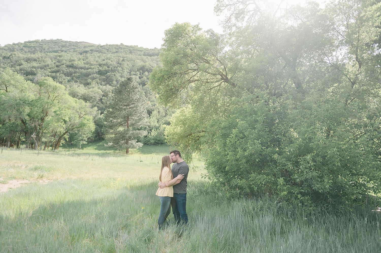 A romantic moment captured in a misty mountain meadow during golden hour.
