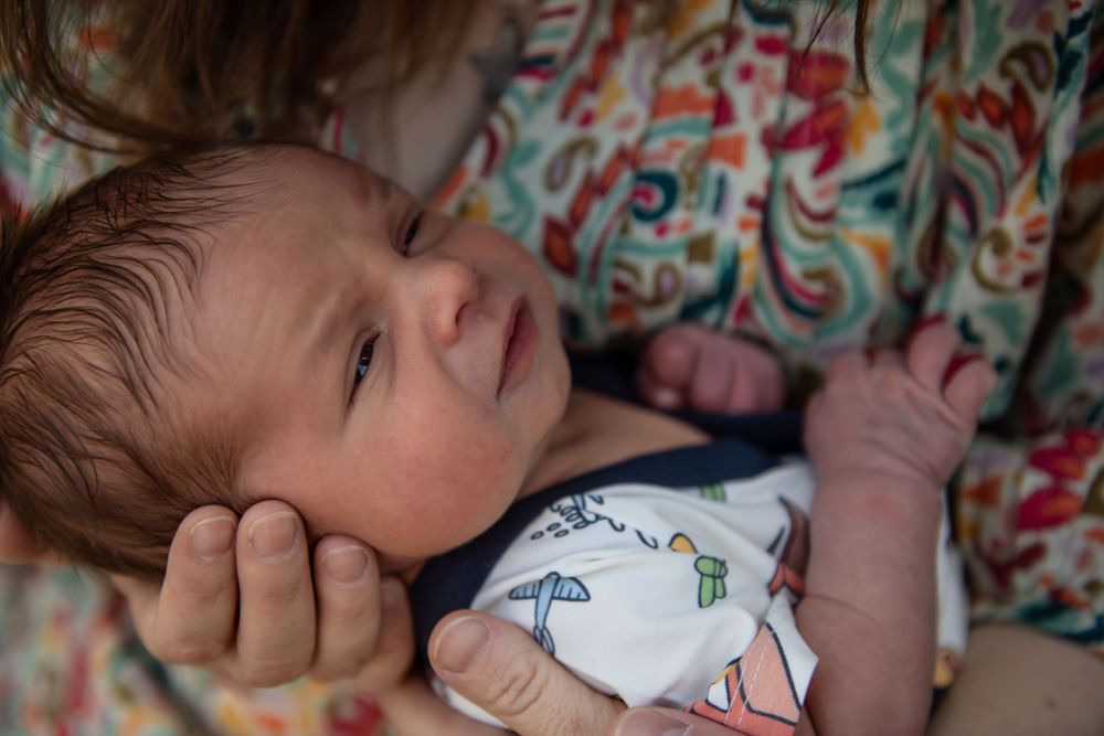 Close-up portrait of a peaceful sleeping newborn in patterned clothing.