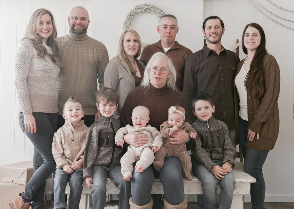 Multi-generational family portrait in neutral tones against a white backdrop.