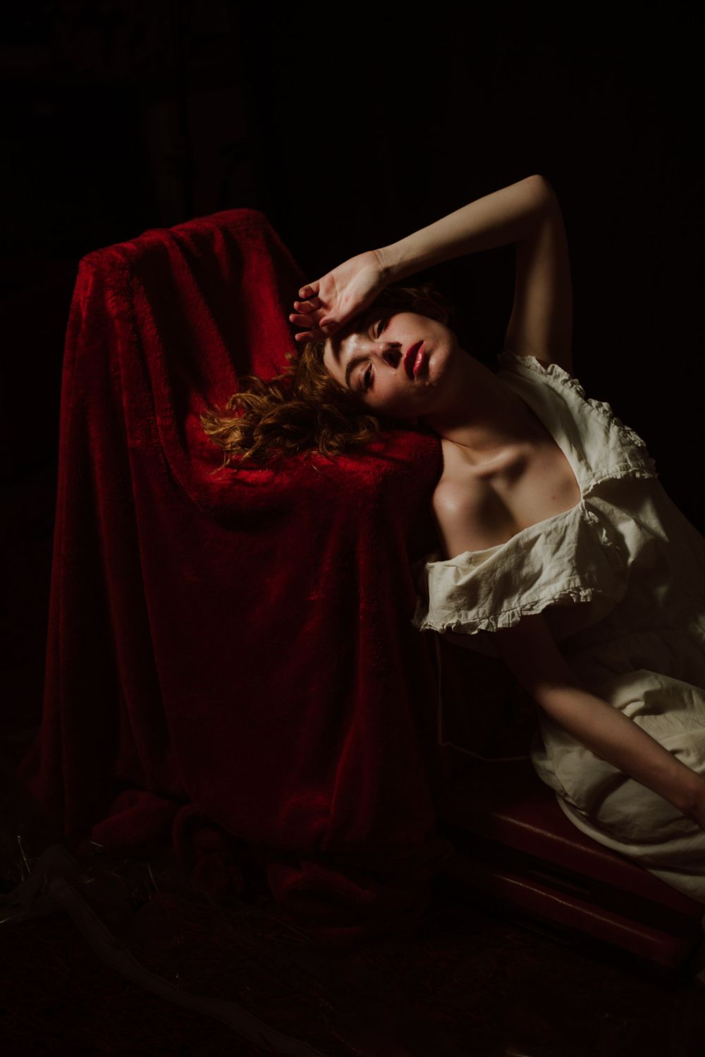 A woman leans into a red velvet chair