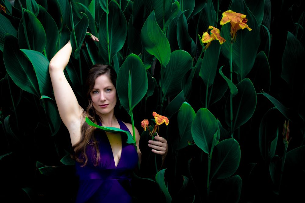 A woman poses amongst the leaves and flowers at Cypress Gardens
