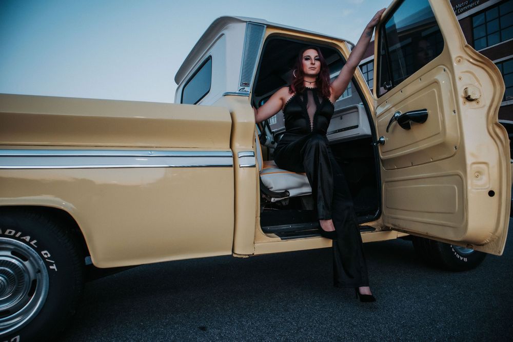 A woman dressed in black steps out of a yellow pickup truck