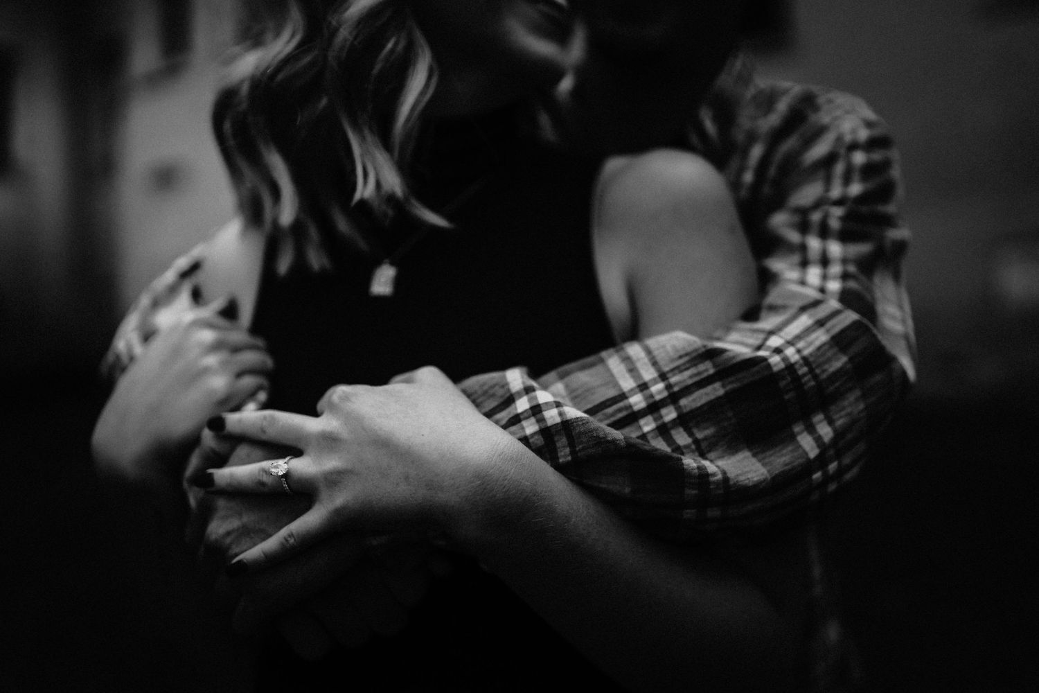 Intimate black and white photo of a couple embracing in dramatic lighting.