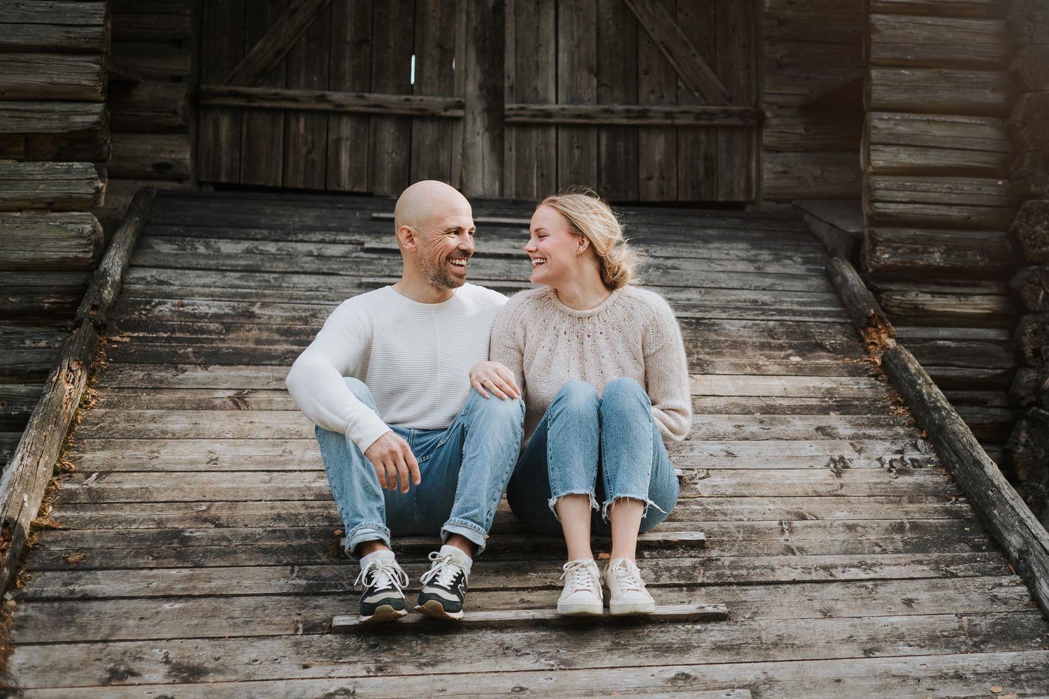 Couple relaxing together on wooden ramp of rustic barn.