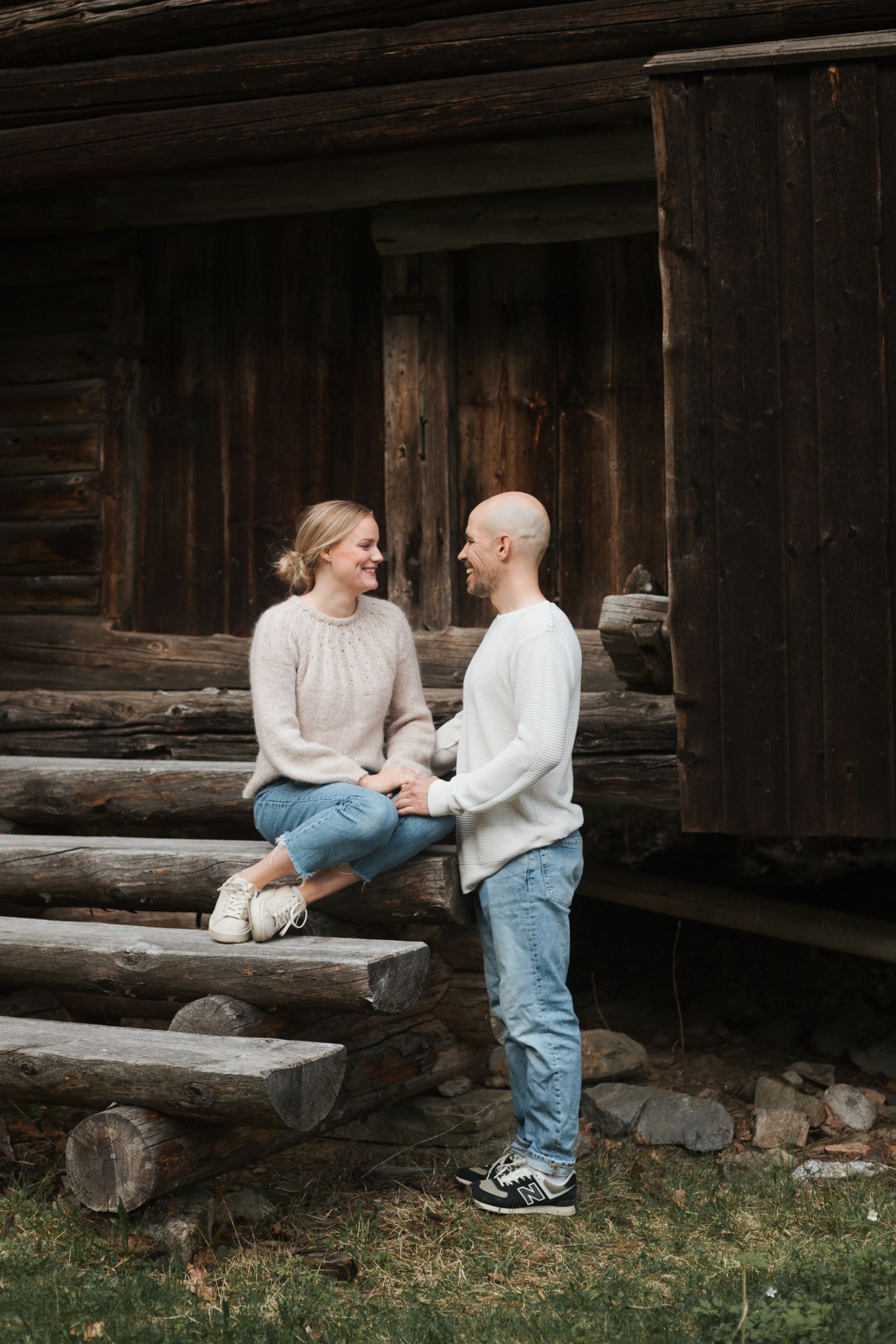 Couple sharing tender moment on wooden steps of rustic log cabin.