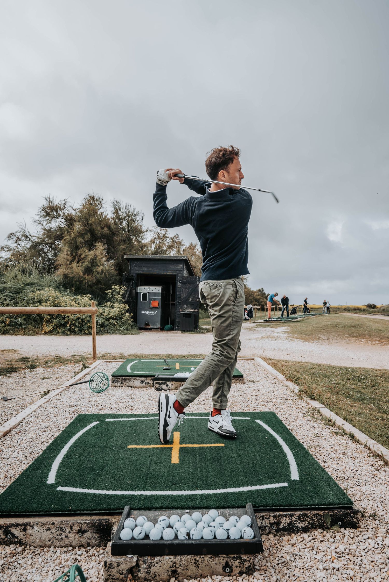 Practice swing demonstration on outdoor golf mat showing proper form and technique.