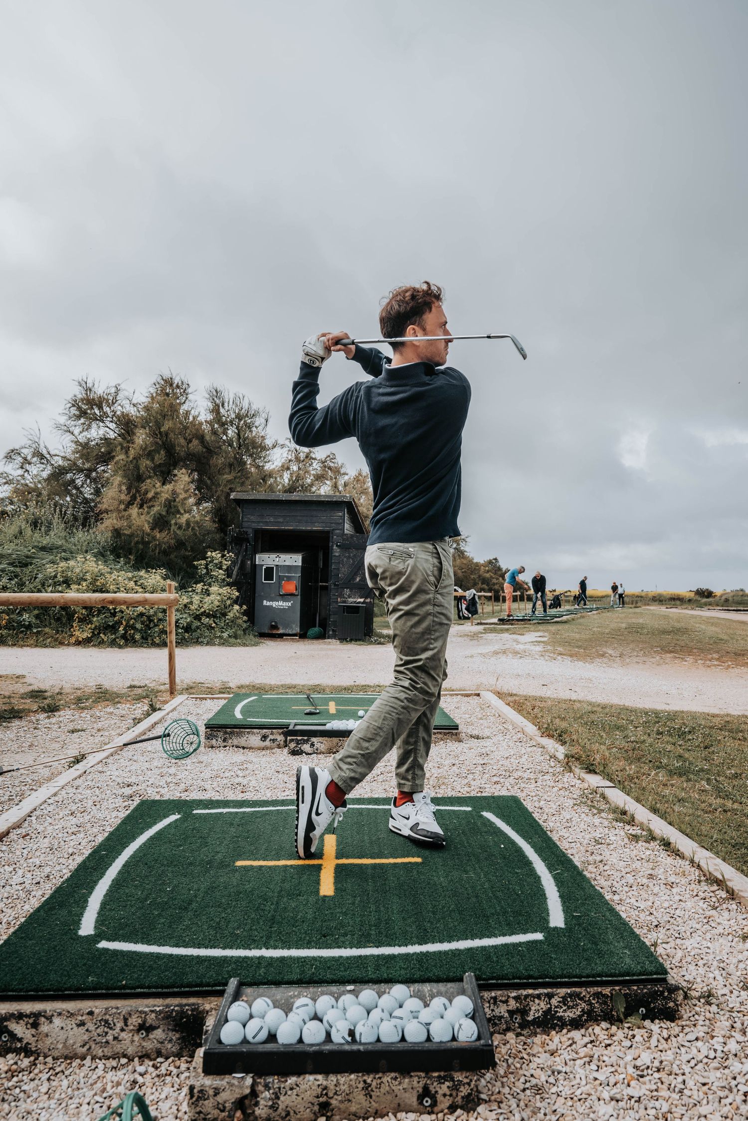 Golfer demonstrating proper backswing position at outdoor practice facility.