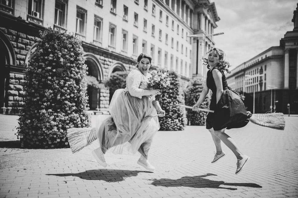 Vintage black and white photo of two friends jumping playfully outdoors.