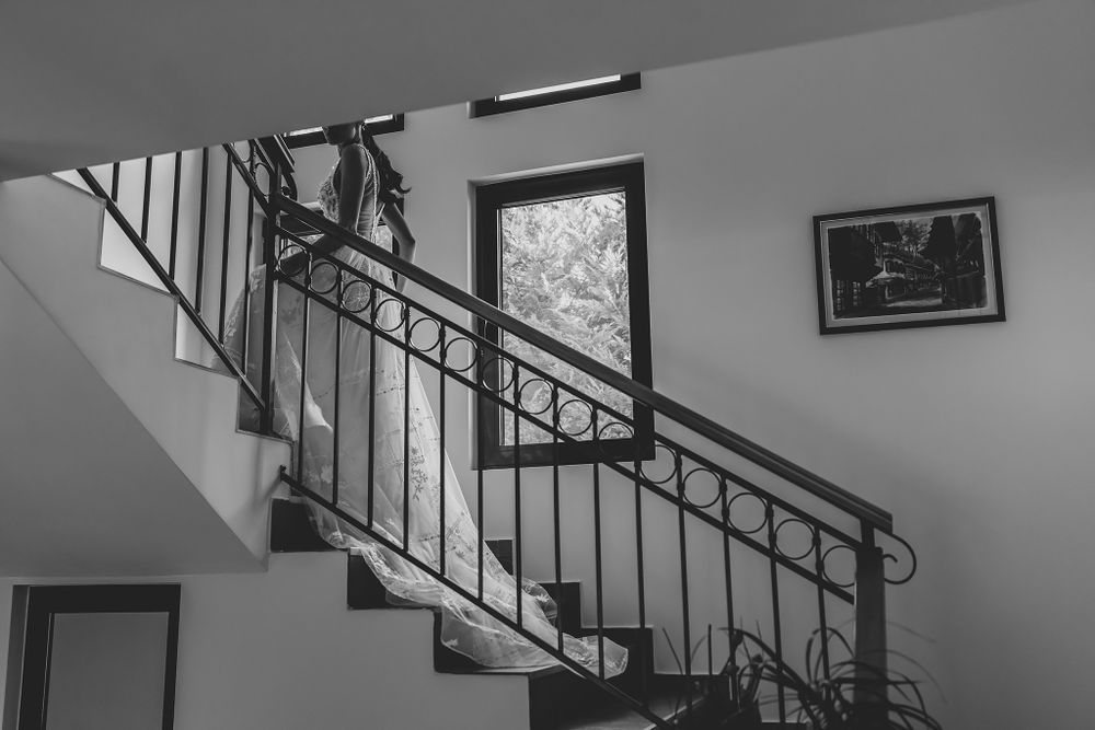A black and white photograph of an elegant staircase with metal railings in a residential interior.