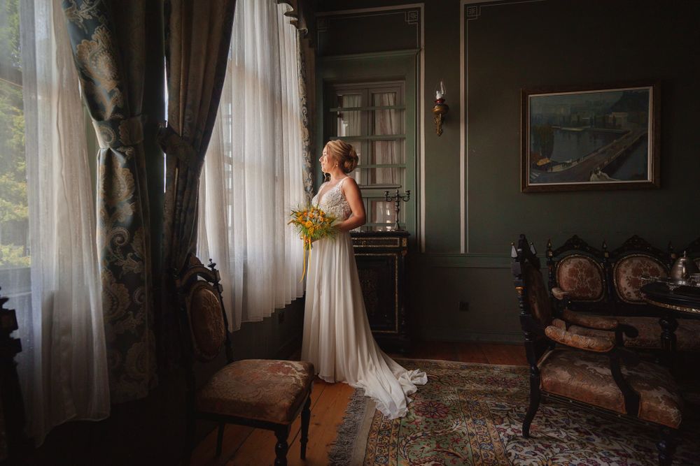 A classic bridal portrait in a vintage room with flowing curtains and antique furniture.