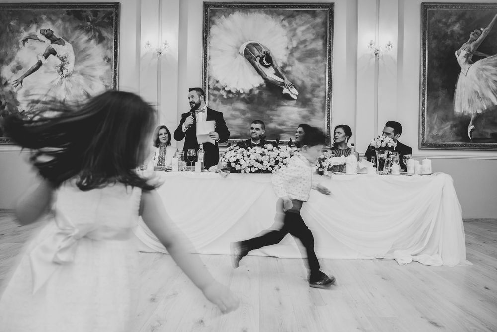 Dynamic reception scene with motion blur as guests dance past formal head table.