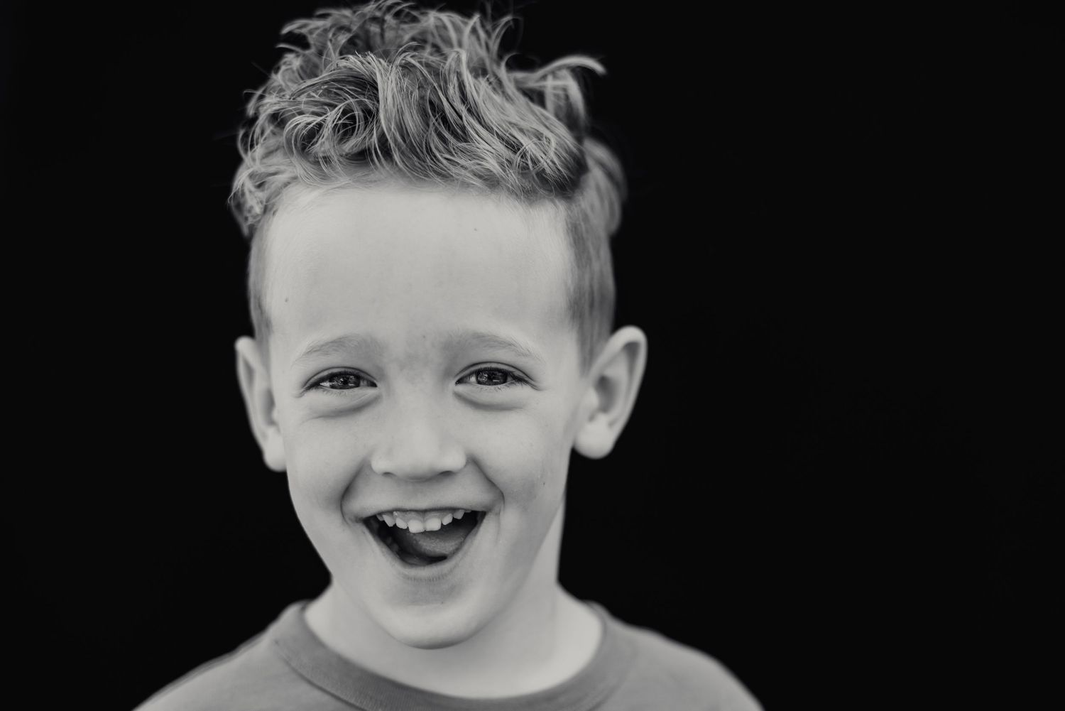 A black and white close-up portrait showing a joyful expression.
