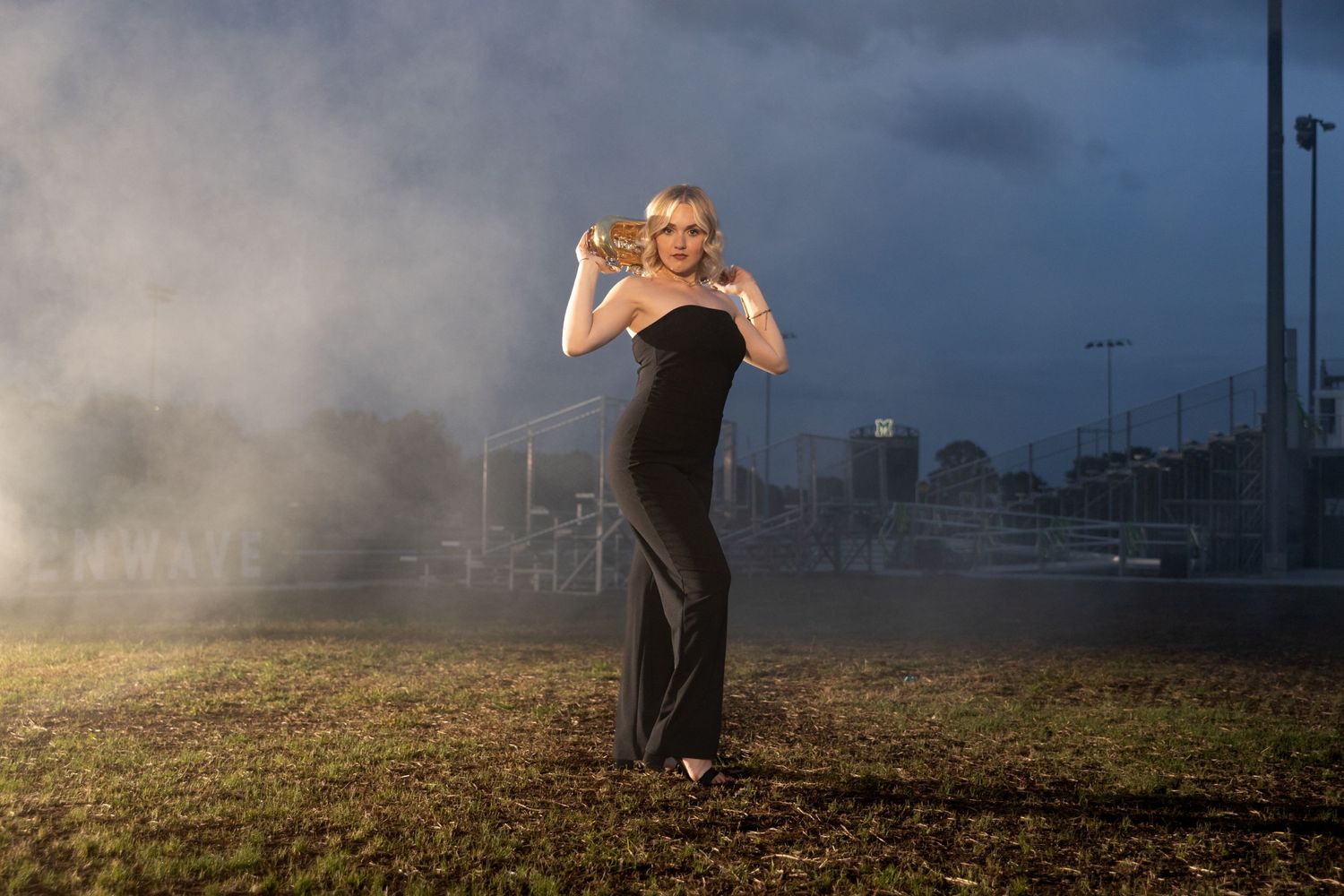 High school senior at Mattoon, Illinois strikes awesome pose with her band instrument on the football field.