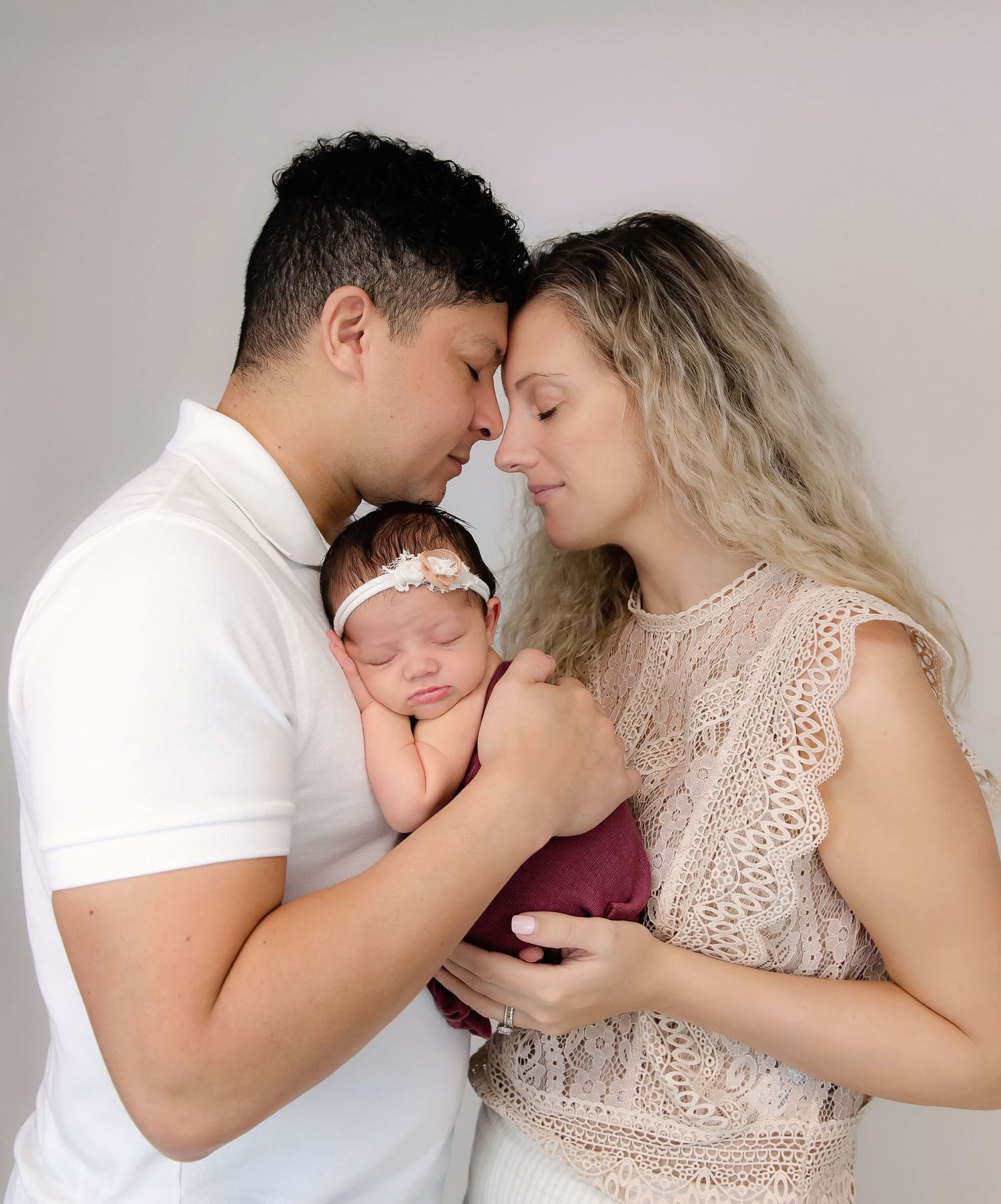 Intimate studio portraits against white backdrop showing tender family moments.