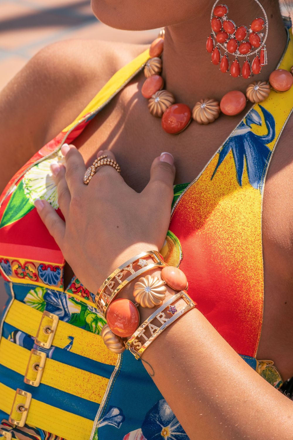 Detailed shot of coral statement jewelry and colorful printed summer fashion accessories.