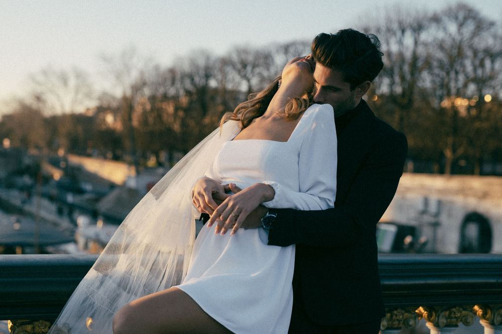 Romantic couple sharing tender moments along a waterfront at sunset.