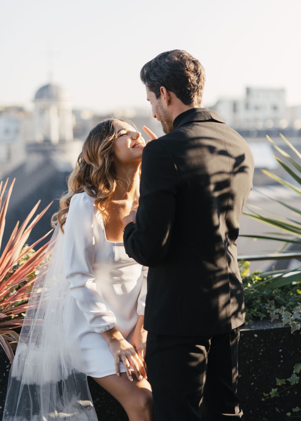 Couple in contrasting outfits dancing together on an outdoor terrace.