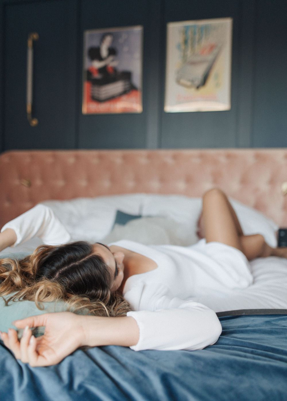 Person in white lying peacefully on a bed with decorative wall art visible.