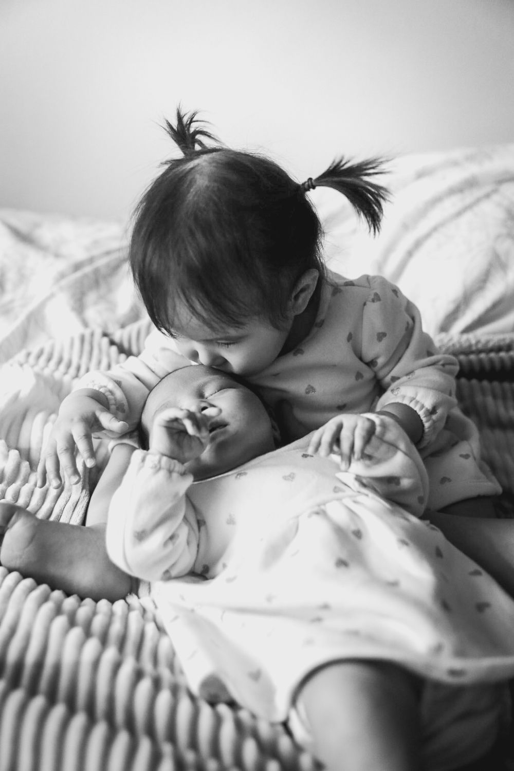 Black and white series of a sleeping baby in soft bedding.