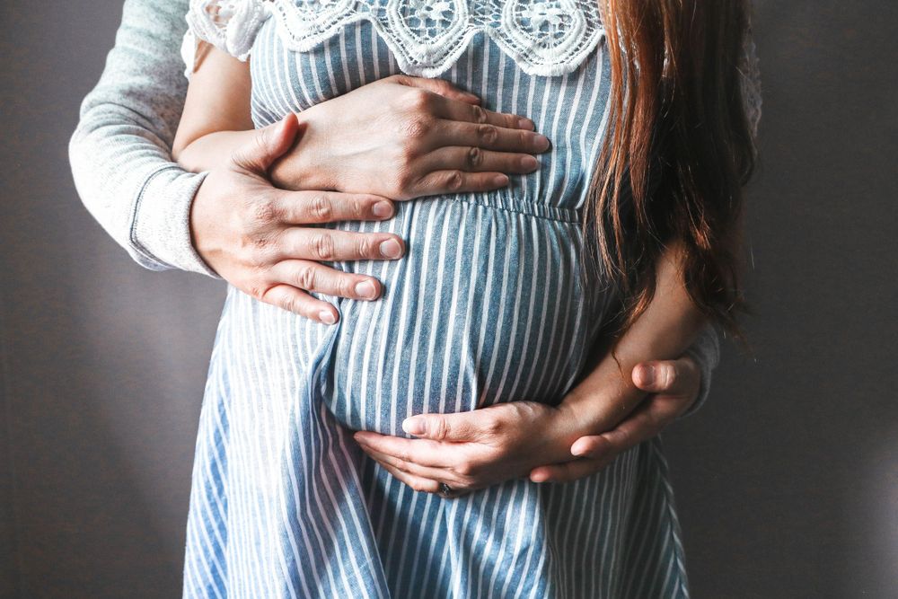 Maternity photo series showing close-up of hands cradling a pregnant belly.