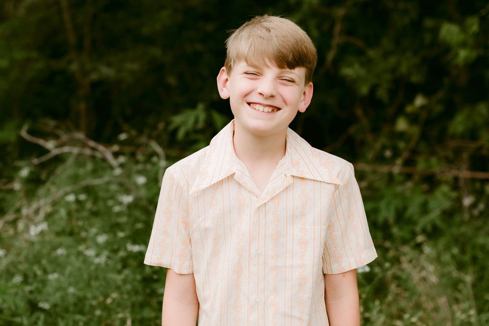 A sunny outdoor portrait against a natural green background.