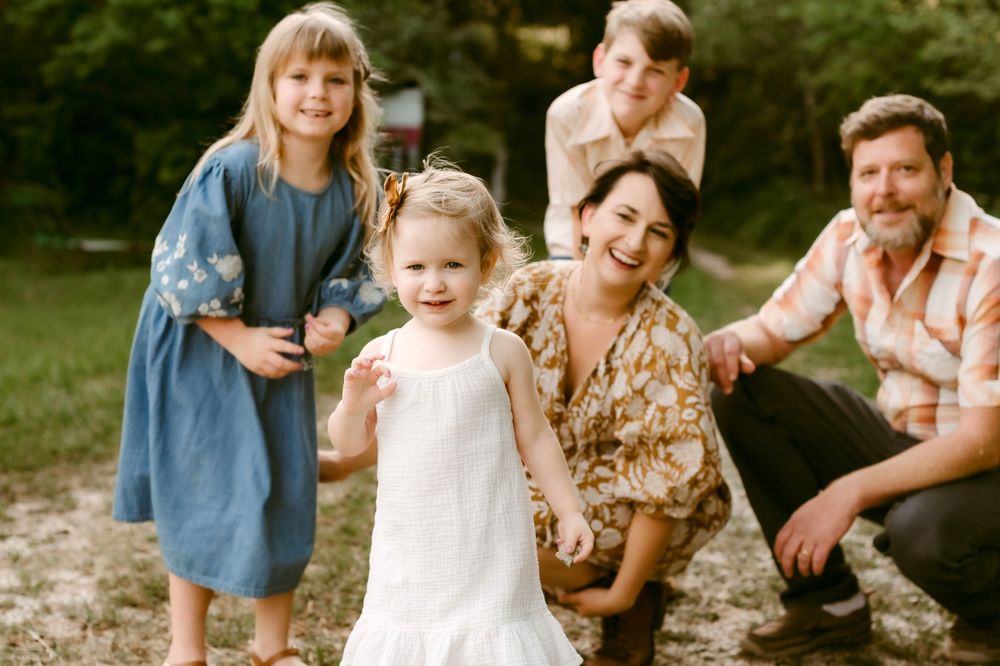 A casual outdoor family portrait with everyone smiling in natural lighting.