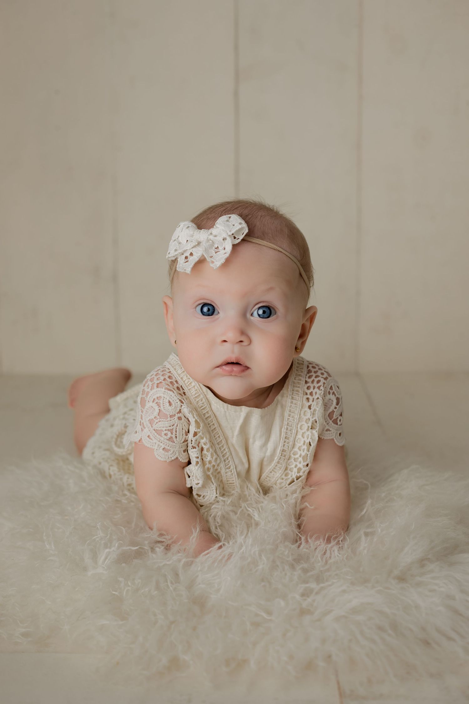 Baby girl staring into the camera dressed in lace for her 3 month milestone studio session.