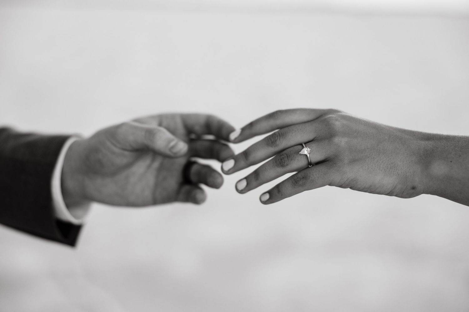 Hands nearly touching with beautiful wedding ring showing black and white during wedding shoot
