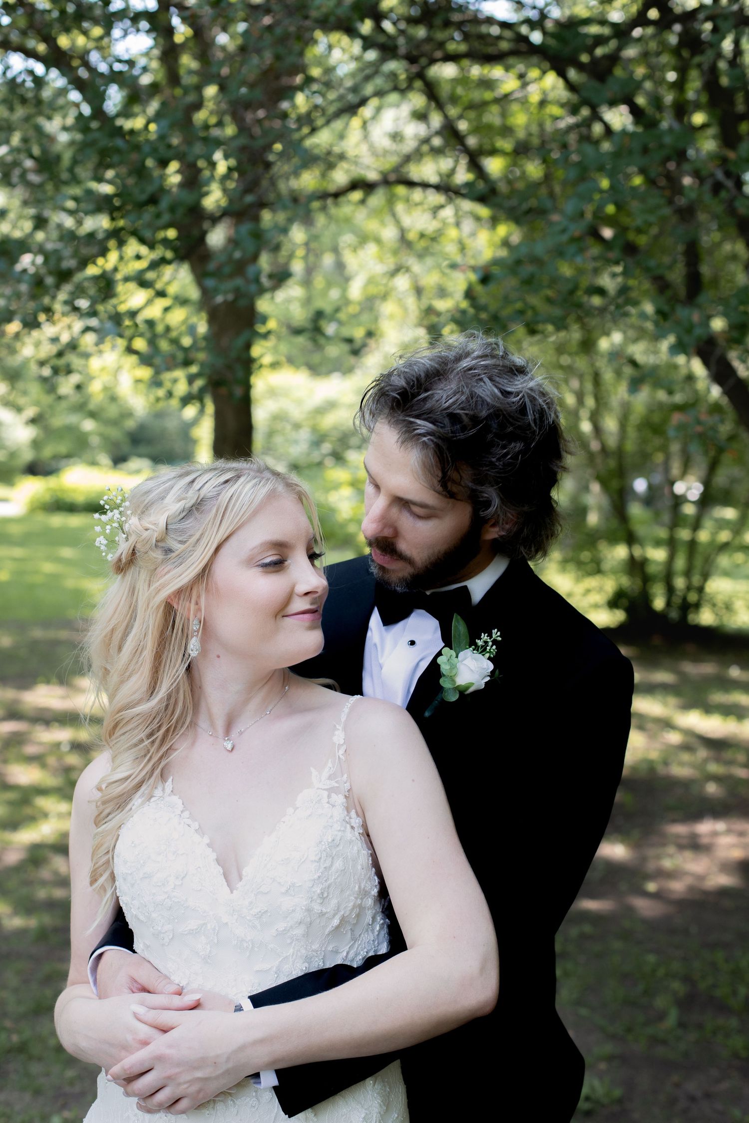 A romantic wedding portrait of a couple embracing in a sunlit garden setting.