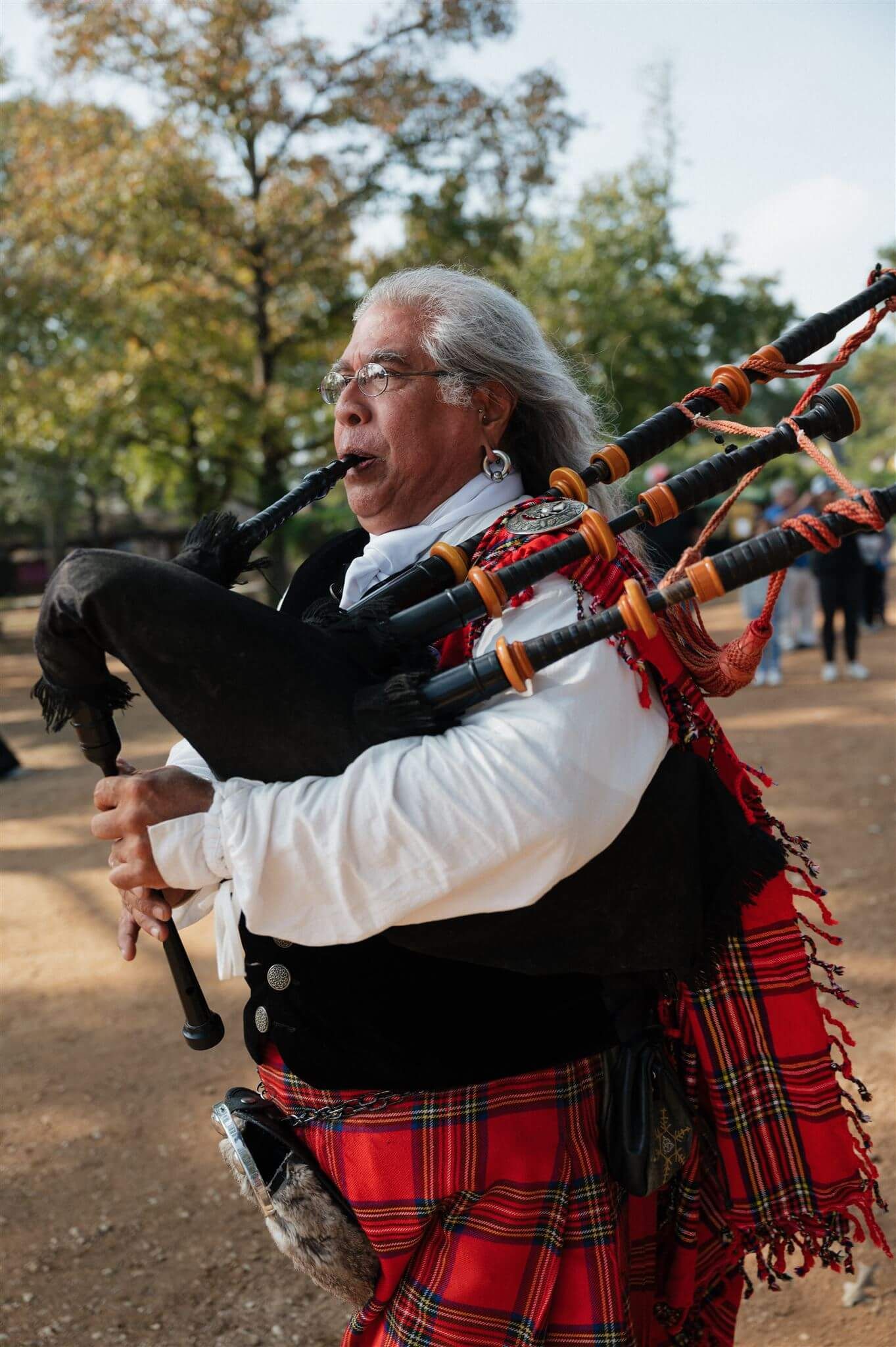 Bagpiper in traditional Scottish dress plays music at Renaissance festival.