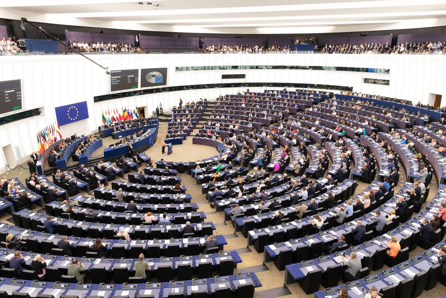 Interior view of European Parliament hemicycle during session with MEPs present.