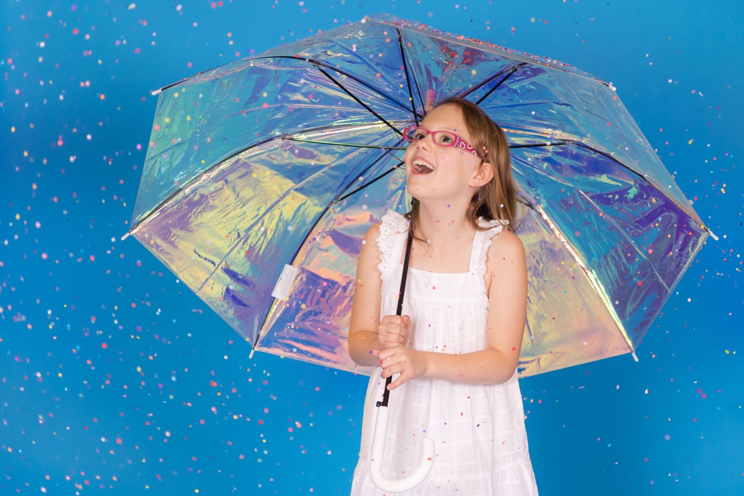 child holding irridescent umbrella on savage blue jay backdrop with confetti in studio in clayton new jersey Gloucester