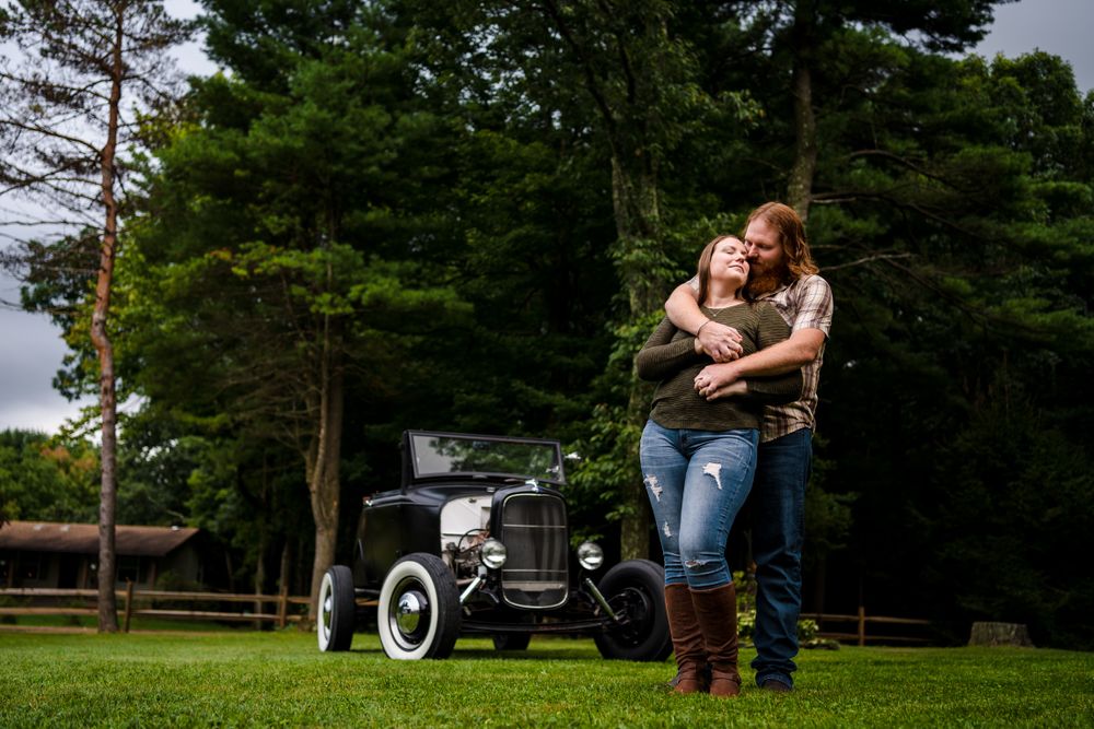 Rustic outdoor scene with vintage truck and pine trees in background.