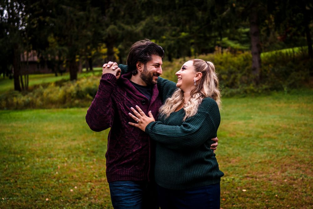 A couple shares a joyful moment together in a lush green outdoor setting during golden hour.