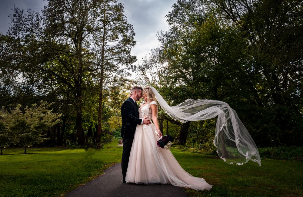 A romantic wedding photo with a flowing veil captured in a scenic park setting.