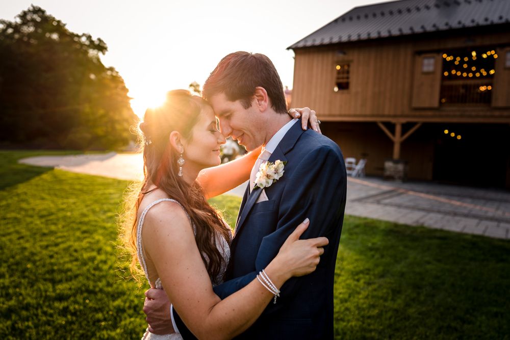 Golden sunset light illuminates a romantic moment outside a rustic venue.