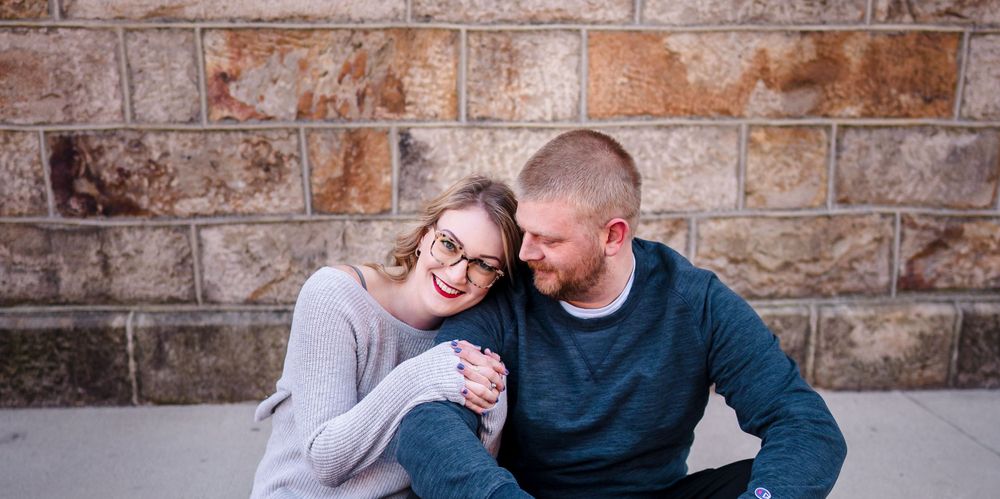 Intimate couple's portrait against rustic brick wall background.