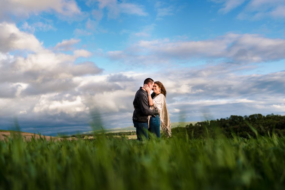 Romantic couple silhouetted against blue sky and green grass.