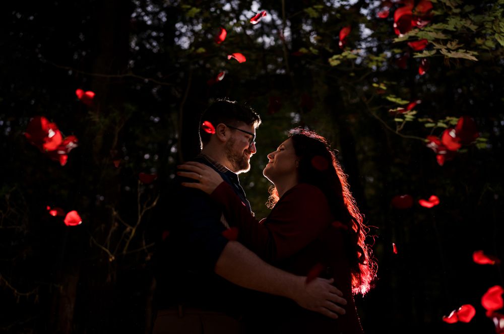 Intimate nighttime portrait with glowing red heart bokeh lights in background.