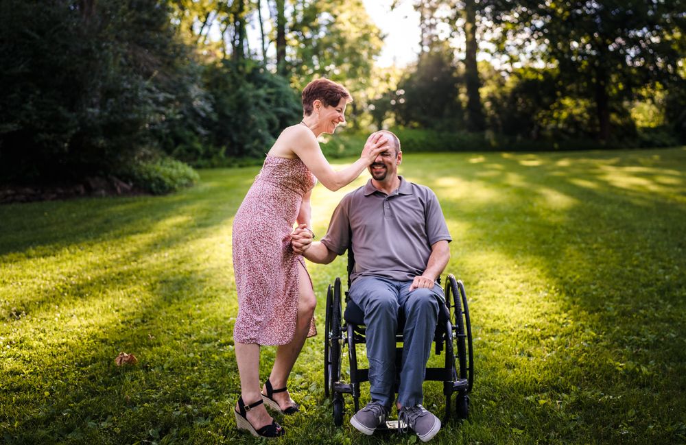 A couple shares joyful moments together in a sunlit grassy field.