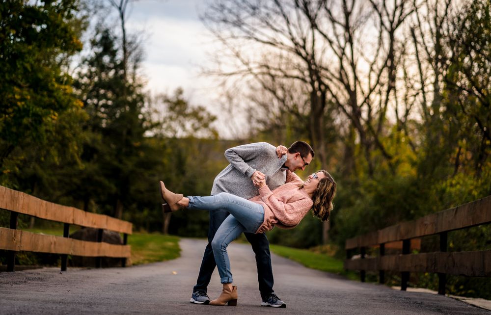 A couple shares playful moments on a wooden bridge during sunset.