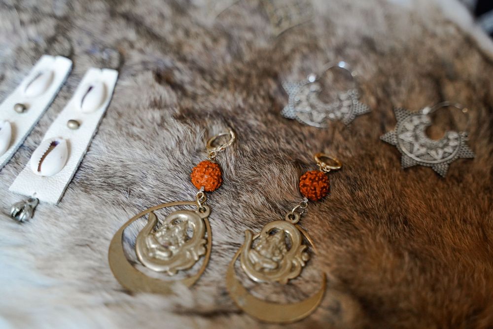 Close-up of delicate crystal earrings with orange accents on a textured surface.
