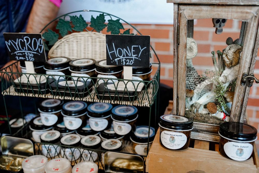 Retail display of honey products and candles arranged on vintage-style metal racks.