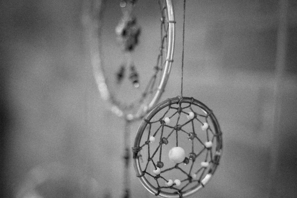 Black and white artistic photo of delicate wire dream catcher ornaments.