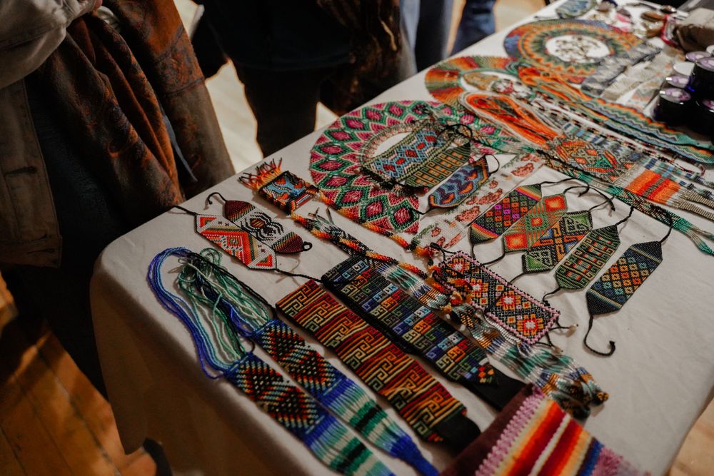 Colorful display of artisanal scarves and textiles laid out on vendor table.
