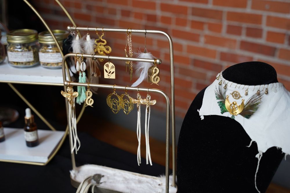 Jewelry display stand with various dangling earrings against a brick wall background.