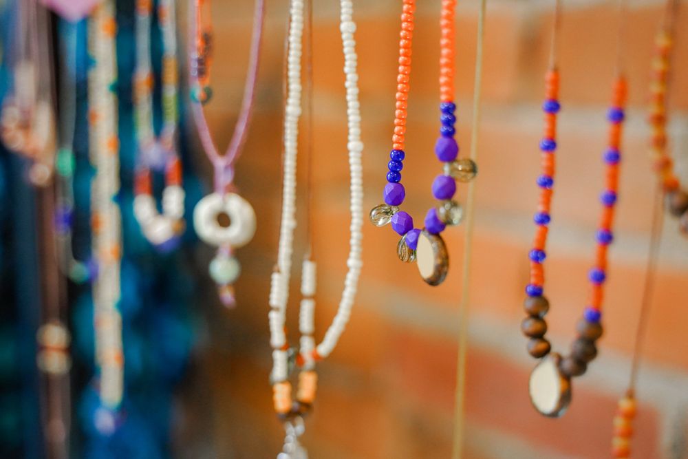 Colorful beaded necklaces and dream catchers displayed on hanging strings.