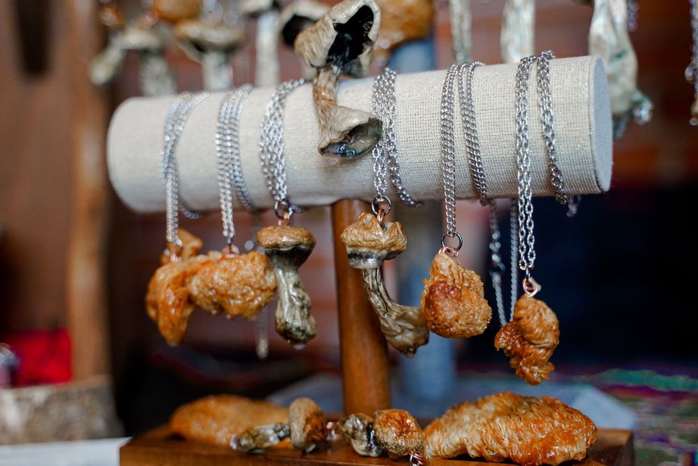 Silver chains and crystal pendants displayed on a white cylindrical stand.