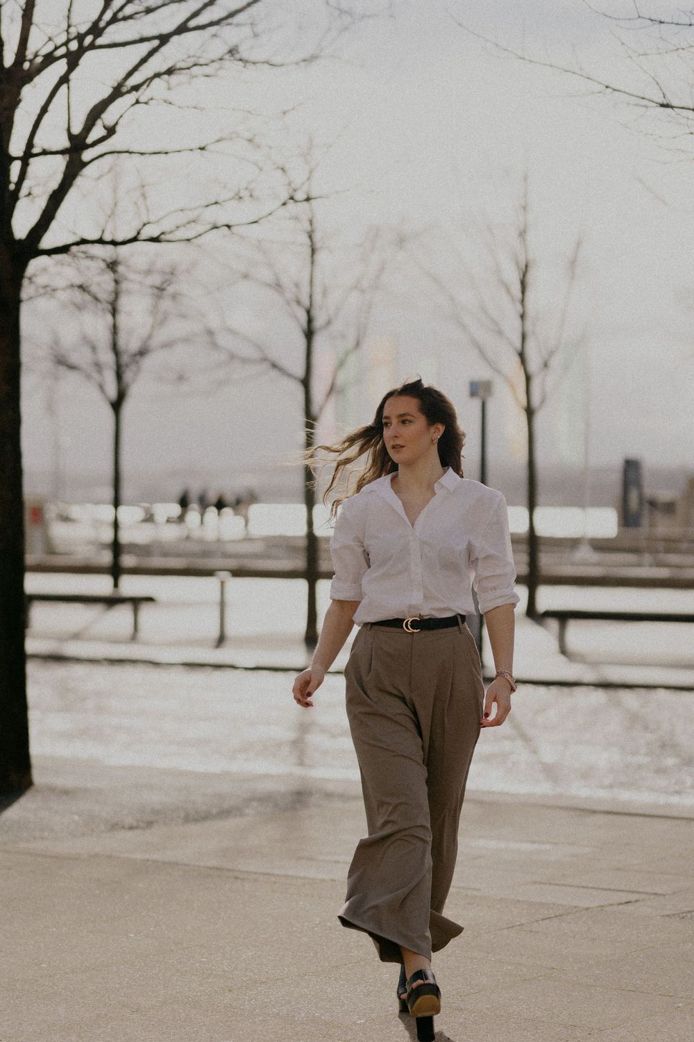 Figure in white shirt and wide pants moves expressively through snowy outdoor setting.